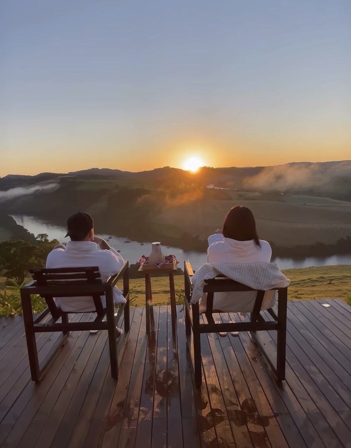 Casal no deck assistindo o nascer do sol